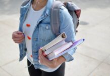 Estudante com cadernos nas mãos em campus da universidade, um dos benefícios do ensino presencial.