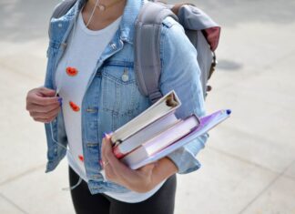 Estudante com cadernos nas mãos em campus da universidade, um dos benefícios do ensino presencial.